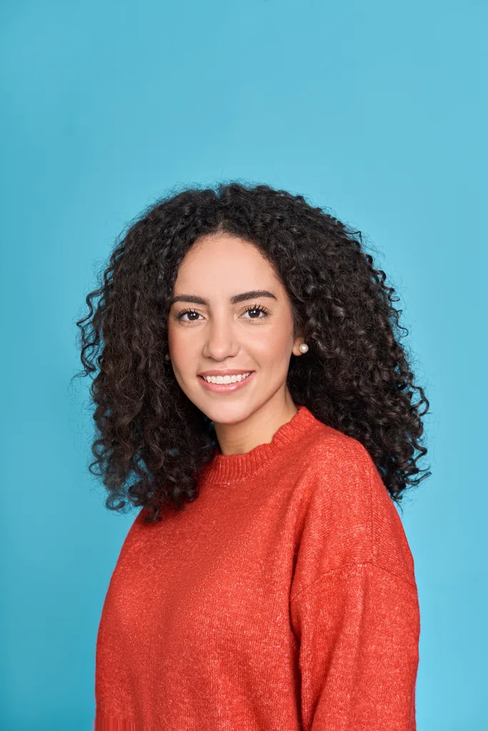 Foto profissional de mulher com cabelo cacheado em suéter laranja